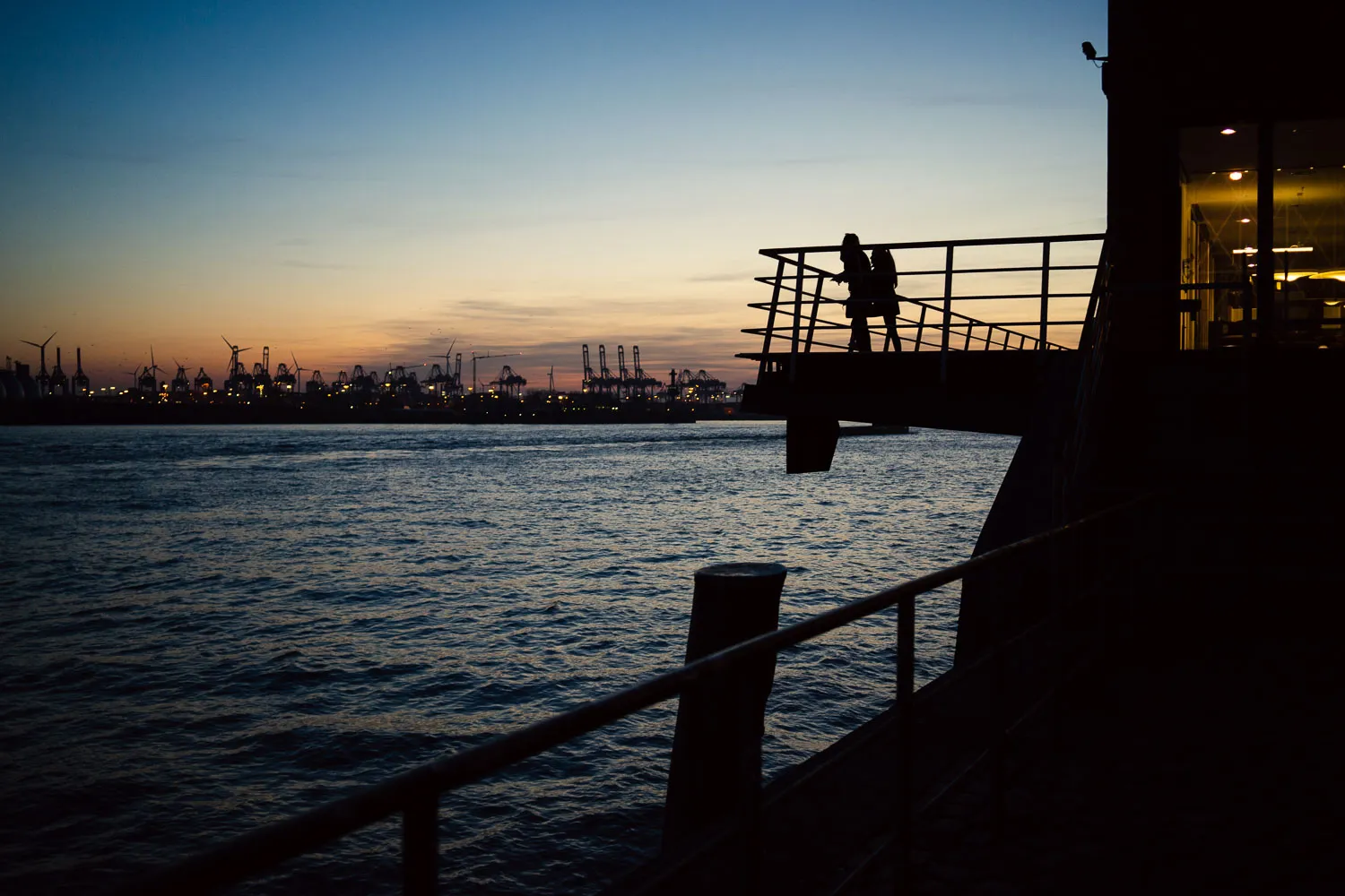 People at viewpoint, Hamburg's harbour at dusk