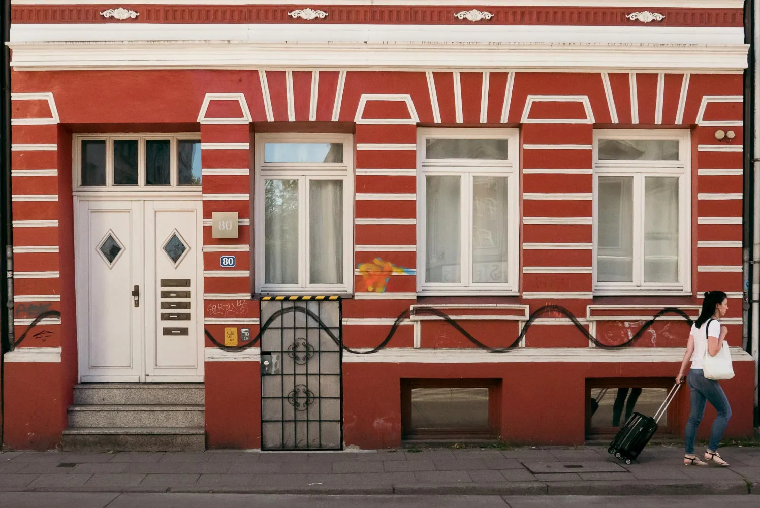 Woman with suitcase following painting at wall